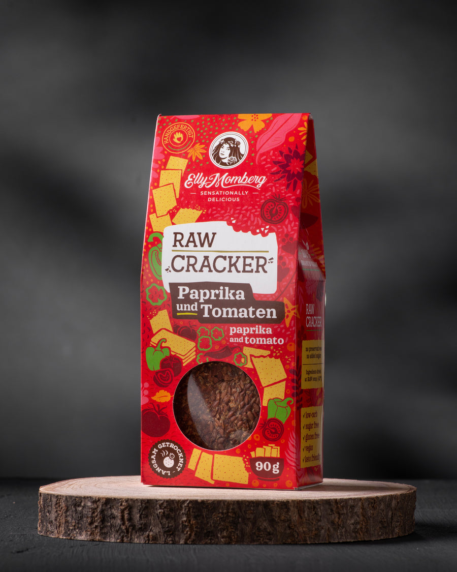 Red packaging of raw crackers with paprika and tomatoes on a dark background