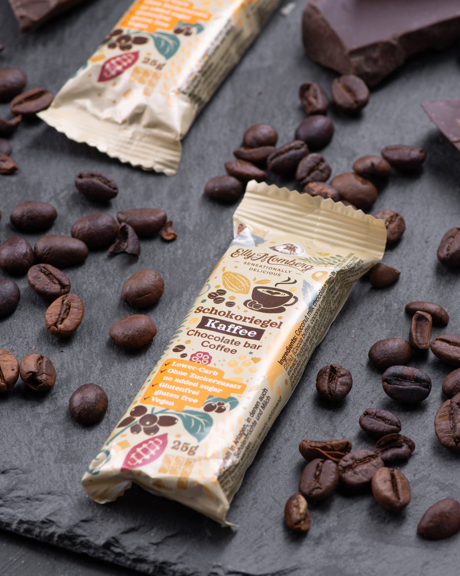 Chocolate bars with coffee flavor packaging surrounded by coffee beans on a dark surface