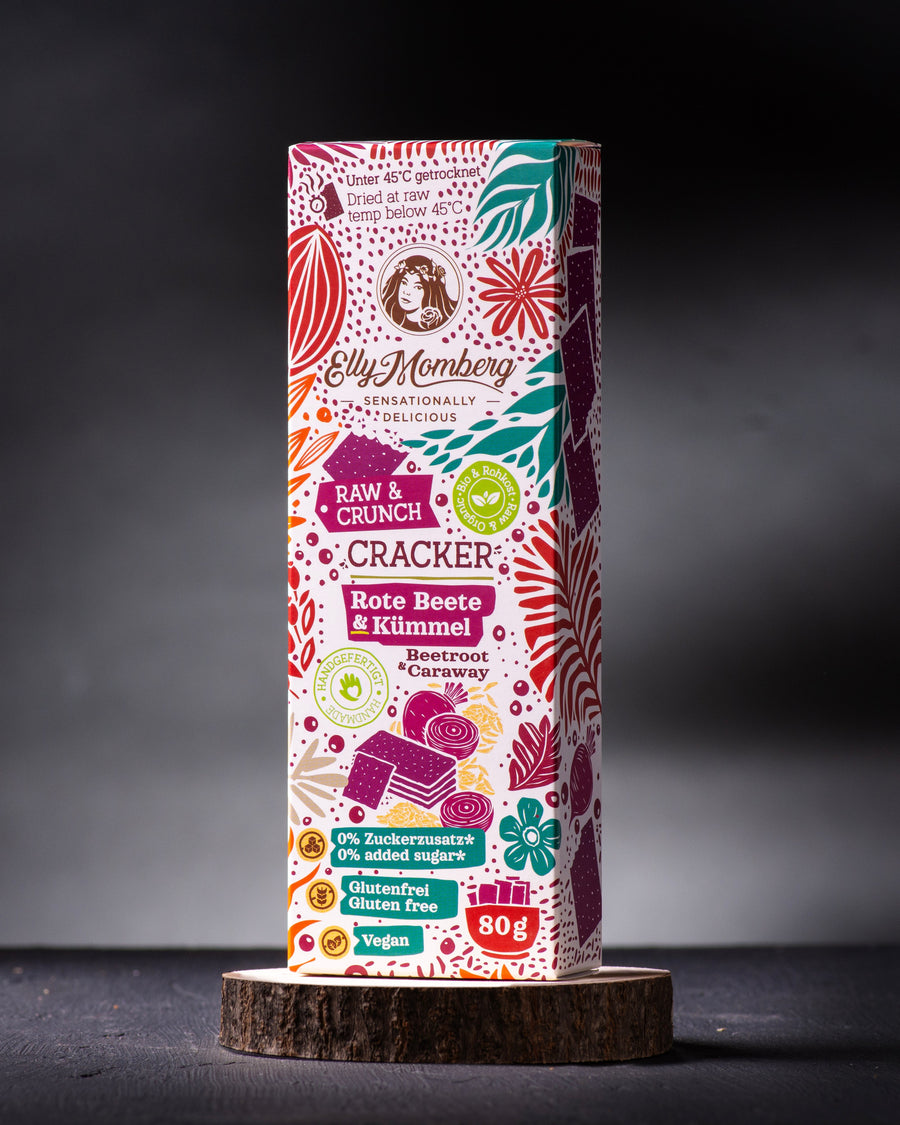 Bio Rohkost Cracker Rote Beete mit Kümmel, vegan und glutenfrei von Elly Momberg, Packung steht auf Holzuntersetzer