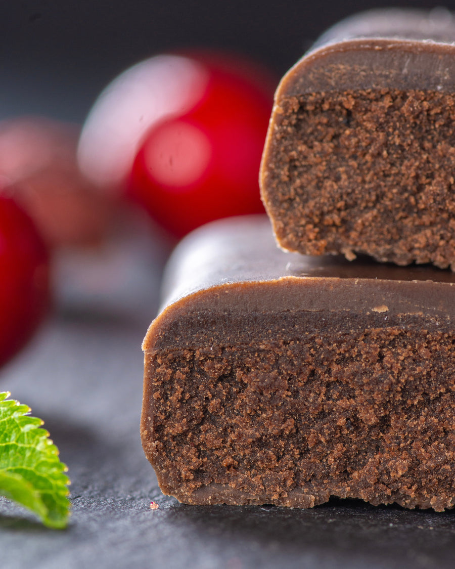 Chocolate gourmet bar with a cross-section on a dark surface with cherry black forest, sugar free, vegan, gluten free, keto. lower carb, diabetics