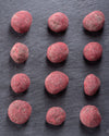 Raspberry balls arranged in a grid on a dark slate surface