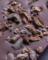 Close-up of dark chocolate bar with cacao nibs on a dark background