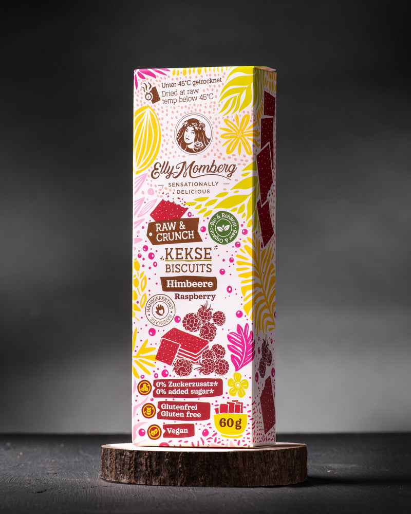 Bio Rohkost Kekse Himbeere ohne Zuckerzusatz und glutenfrei von Elly Momberg, Packung auf Holzuntersetzer 