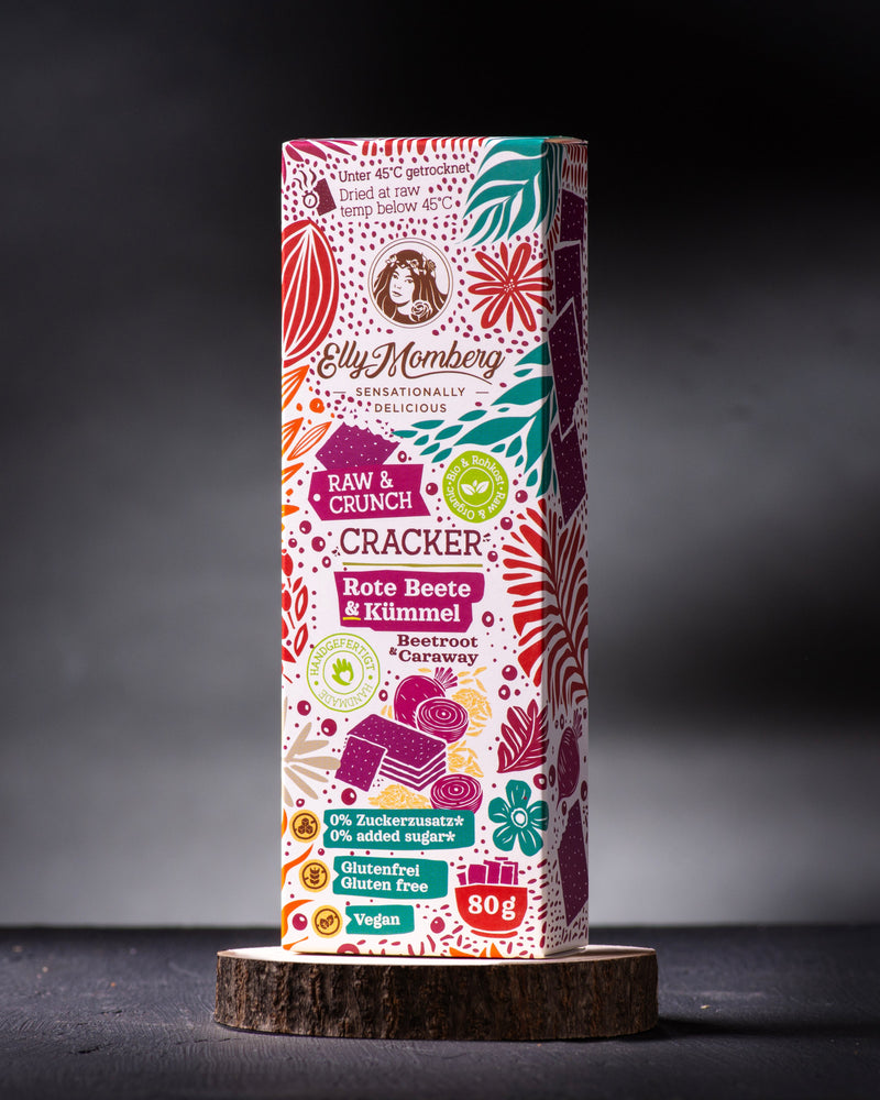 Bio Rohkost Cracker Rote Beete mit Kümmel, vegan und glutenfrei von Elly Momberg, Packung steht auf Holzuntersetzer

