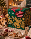 Veganer Adventskalender Grün 2026 mit 24 Überraschungen, Schokolade, Pralinen und Riegeln von Elly Momberg, ohne Zuckerzusatz, Keto-freundlich, für Diabetiker, vegan und glutenfrei. Zeigt Adventskalender vor weihnachtlicher Deko und Hund