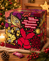 Veganer Adventskalender Deluxe 2026 von Elly Momberg mit 24 Überraschungen ohne Zuckerzusatz, glutenfrei, keto freundlich, und für Diabetiker geeignet in der Farbe bordeaux. Zeigt Adventskalender vor Weihnachtsbaum